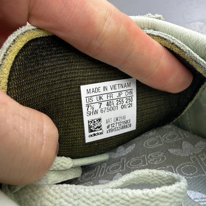Adidas green deck shoes with white accents and logo detailing.
