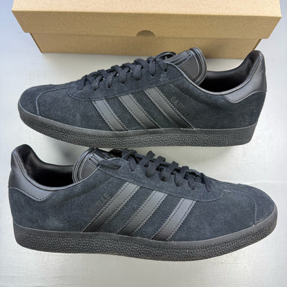 Adidas black trainers in suede with iconic three stripes logo and classic design.