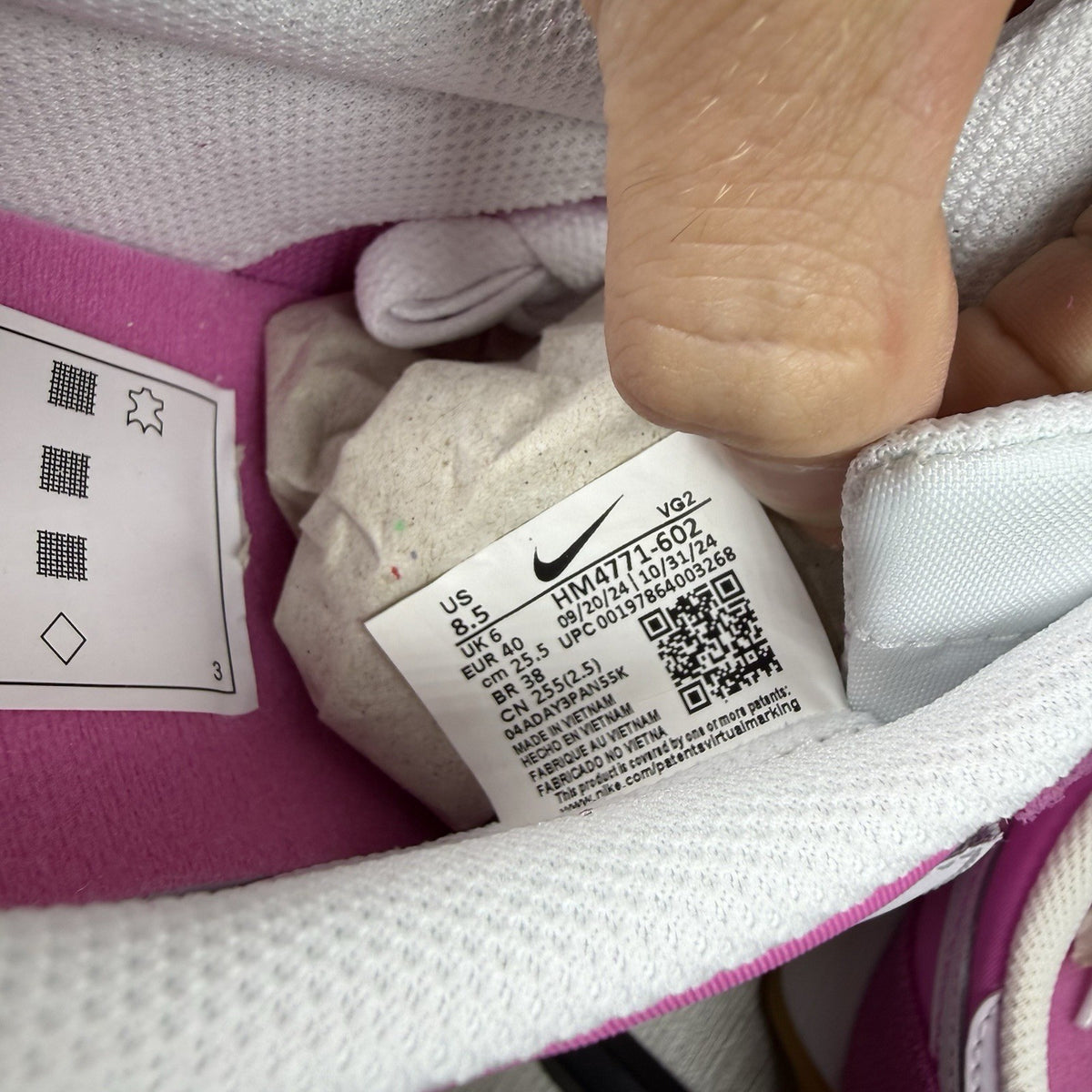 Nike white trainers with pink accents and gum sole, featuring iconic swoosh logo.