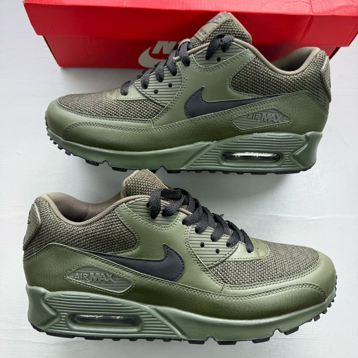 Nike Air Max 90 green trainers with black accents and logo detail.