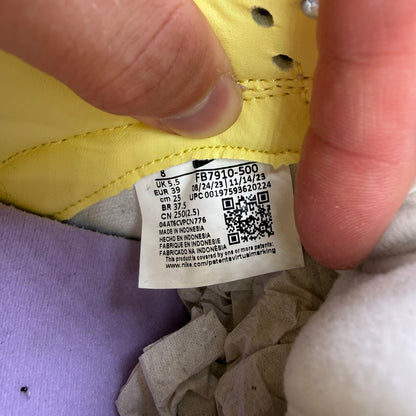 Nike Dunk Low purple trainers with soft yellow accents and classic swoosh logo.