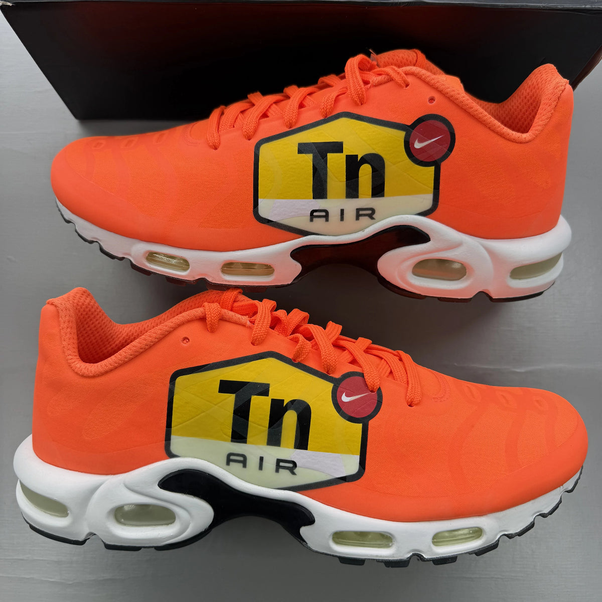 Nike Air Max Plus trainers total orange with large logo and mesh material.