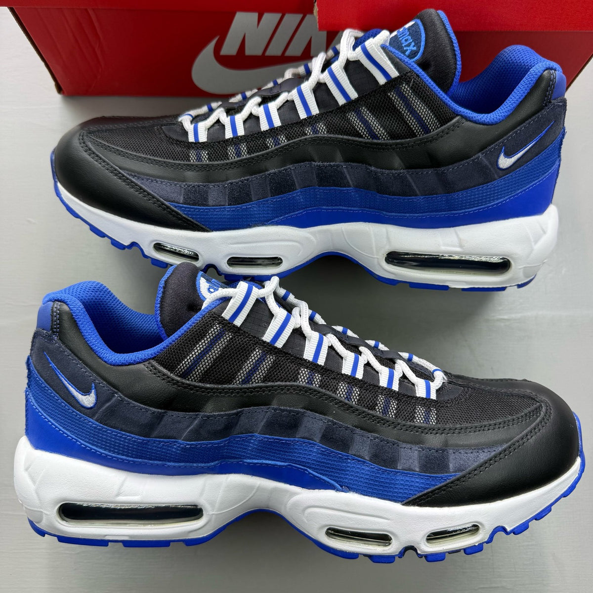 Nike Air Max 95 black trainers with royal blue accents and white detailing.