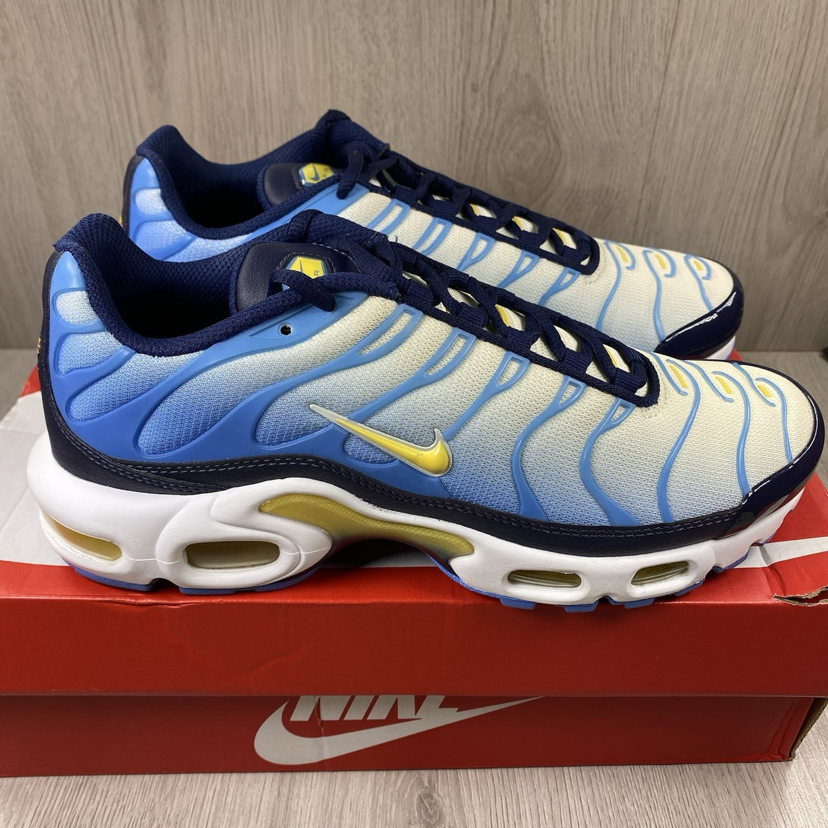 Nike Air Max Plus TN blue trainers with yellow accents and signature swoosh logo.
