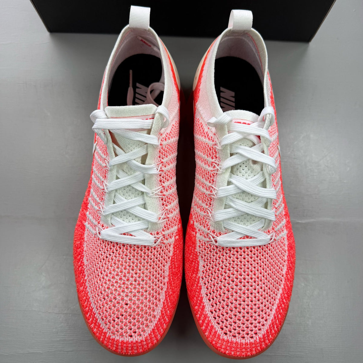 Nike Air VaporMax 2 Flyknit white trainers with hot punch red accents and breathable material.