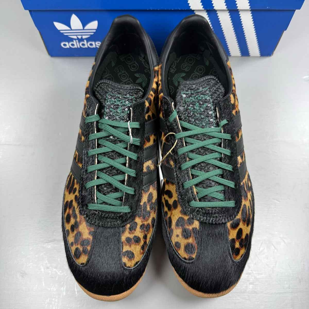 Adidas black trainers with leopard print accents and classic three-stripe logo.