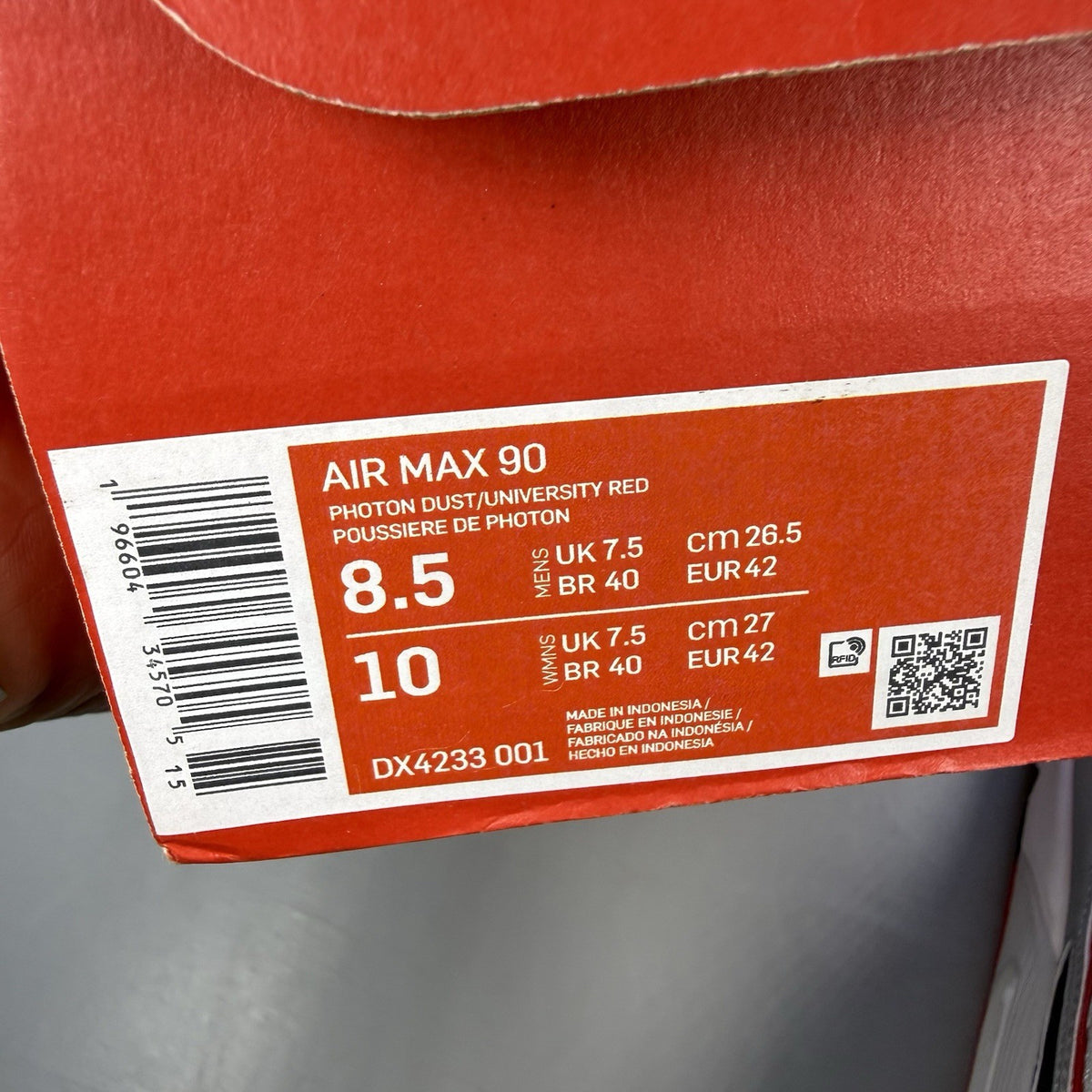 Nike Air Max 90 Icons grey trainers with red accents and white sole, featuring logo details.