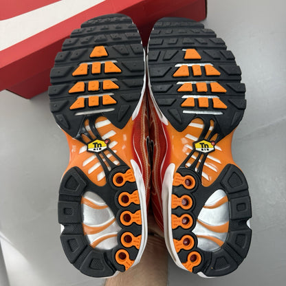 Nike Air Max Plus TN red trainers with signature logo and vibrant orange accents.