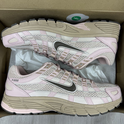 Nike beige trainers with pink accents and mesh detailing, featuring iconic swoosh logo.