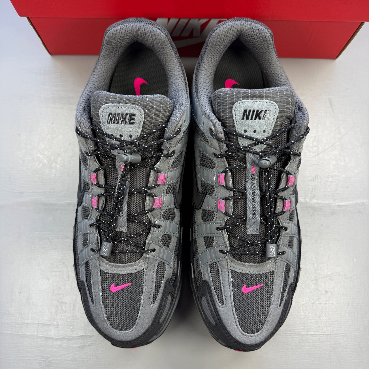 Nike P-6000 grey trainers with pink and black accents, mesh upper and logo detail.
