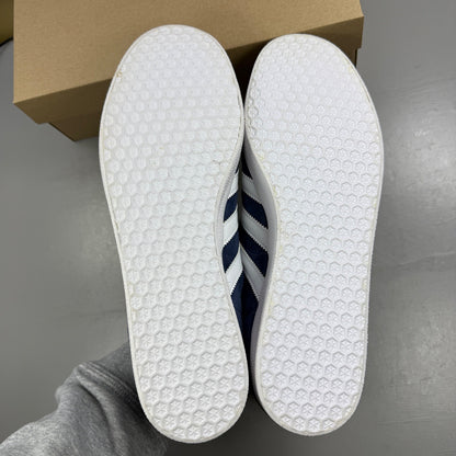 Adidas blue suede trainers with white stripes and logo detailing.