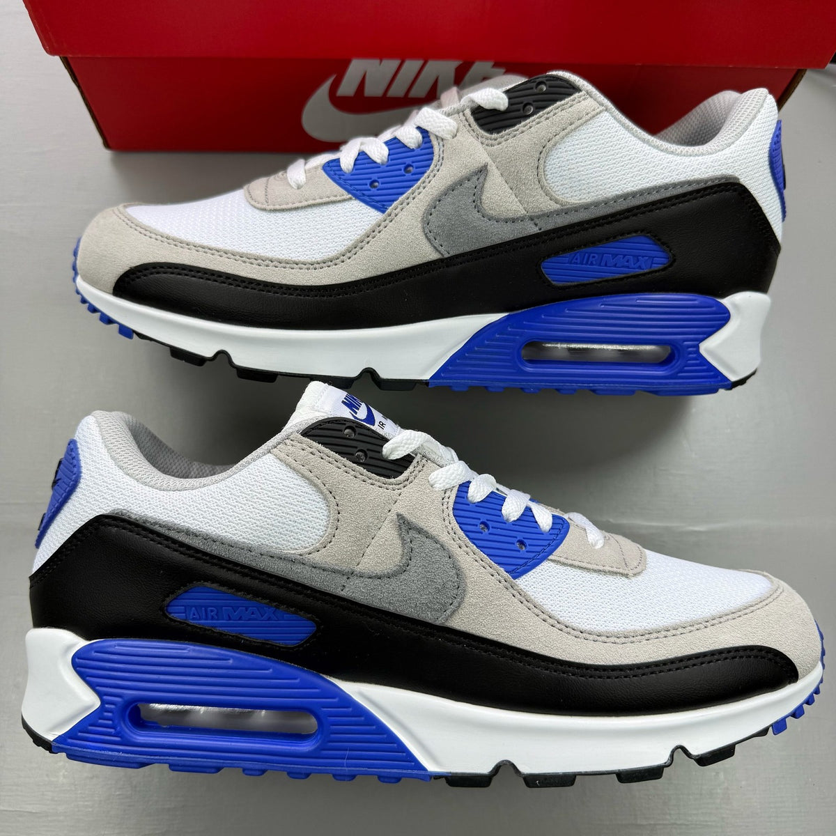 Nike Air Max 90 trainers white grey blue with signature swoosh logo and mesh details.