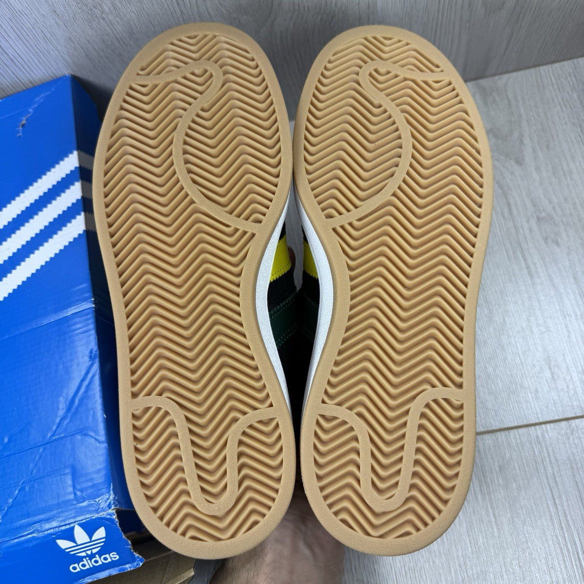 Adidas black trainers with yellow accents and classic three-stripe logo design.