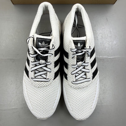 Adidas white trainers with black accents and iconic three stripes design.