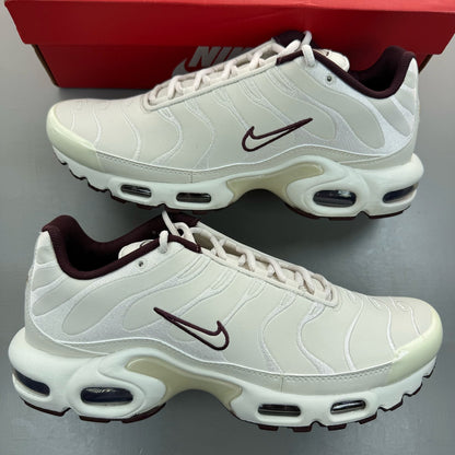 Nike Air Max Plus TN white trainers with burgundy accents and visible logo details.