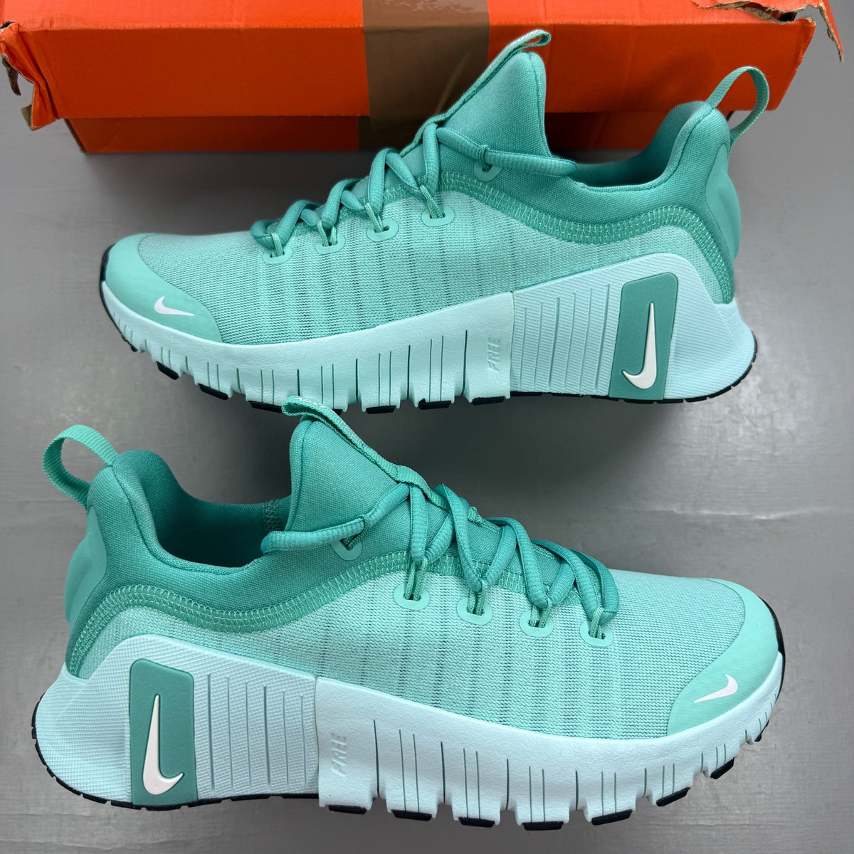 Nike white trainers with bleached turquoise accents and logo detail.