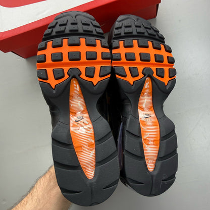 Nike Air Max 95 black trainers with orange camo accents and signature swoosh logo.