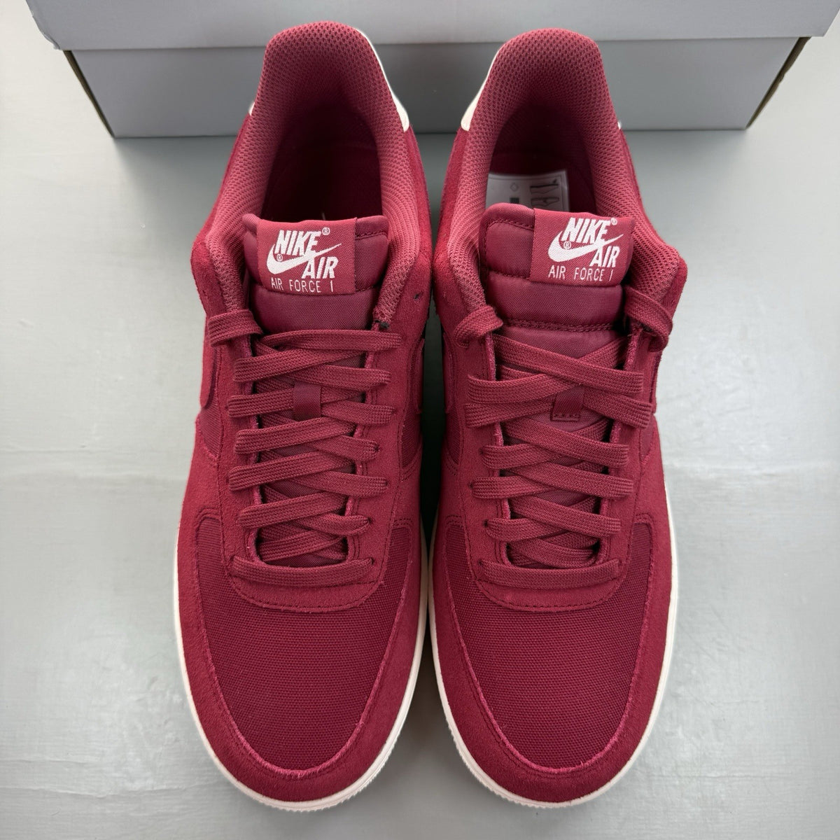 Nike Air Force 1 trainers red suede with white accents and logo detail.