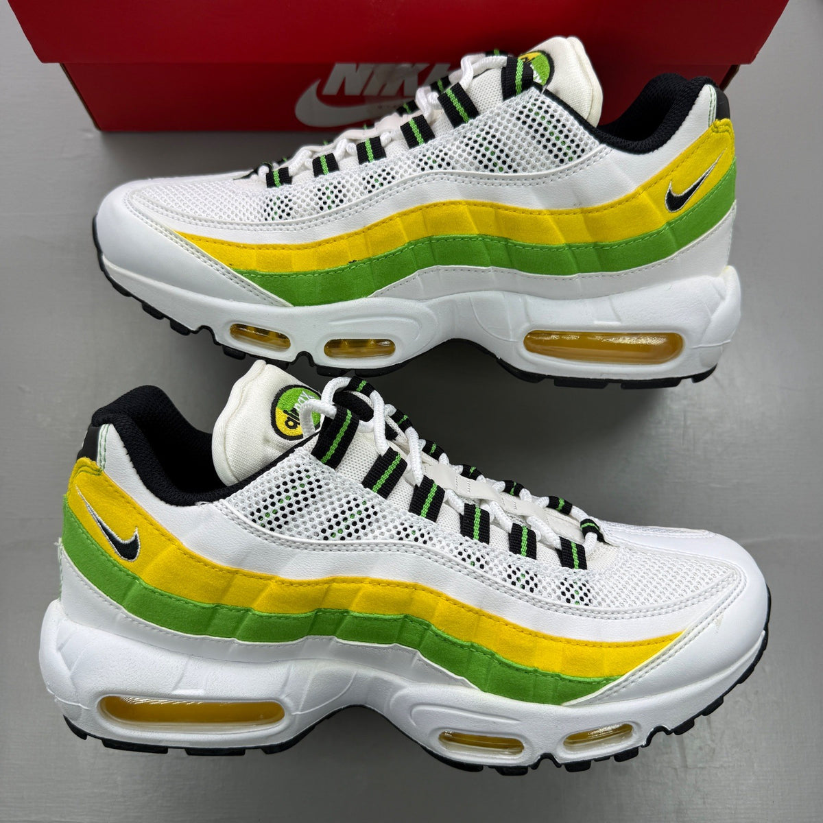 Nike trainers yellow with white accents and green apple details, featuring iconic Air Max design.