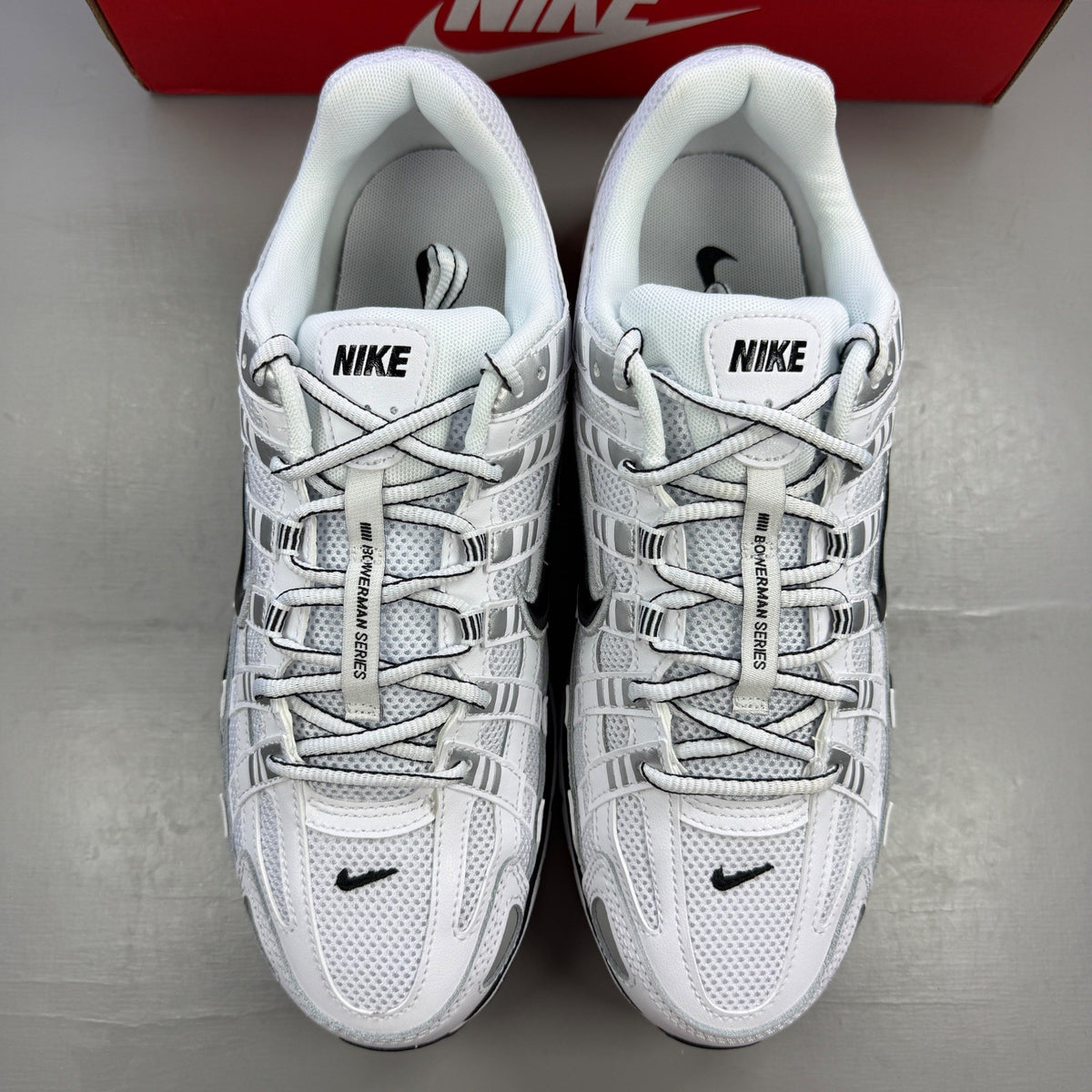 Nike white trainers with metallic silver accents and black detailing, featuring a sleek design.