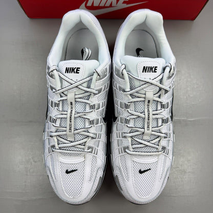 Nike white trainers with metallic silver accents and black detailing, featuring a sleek design.