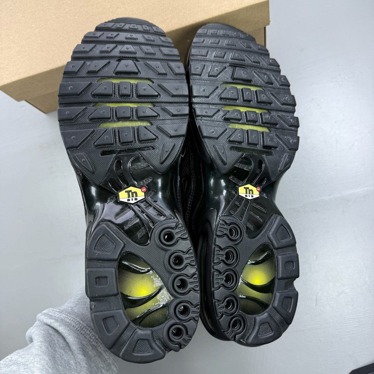 Nike Air Max Plus TN black trainers with distinctive wave pattern and logo detail.