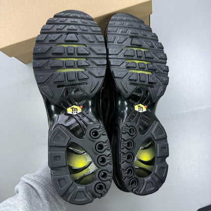 Nike Air Max Plus TN black trainers with distinctive wave pattern and logo detail.