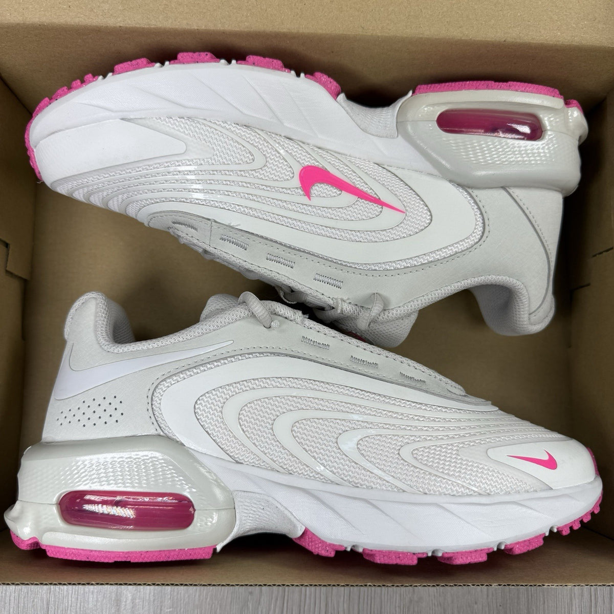 Nike Air Max trainers beige with pink accents and logo detail on the side.