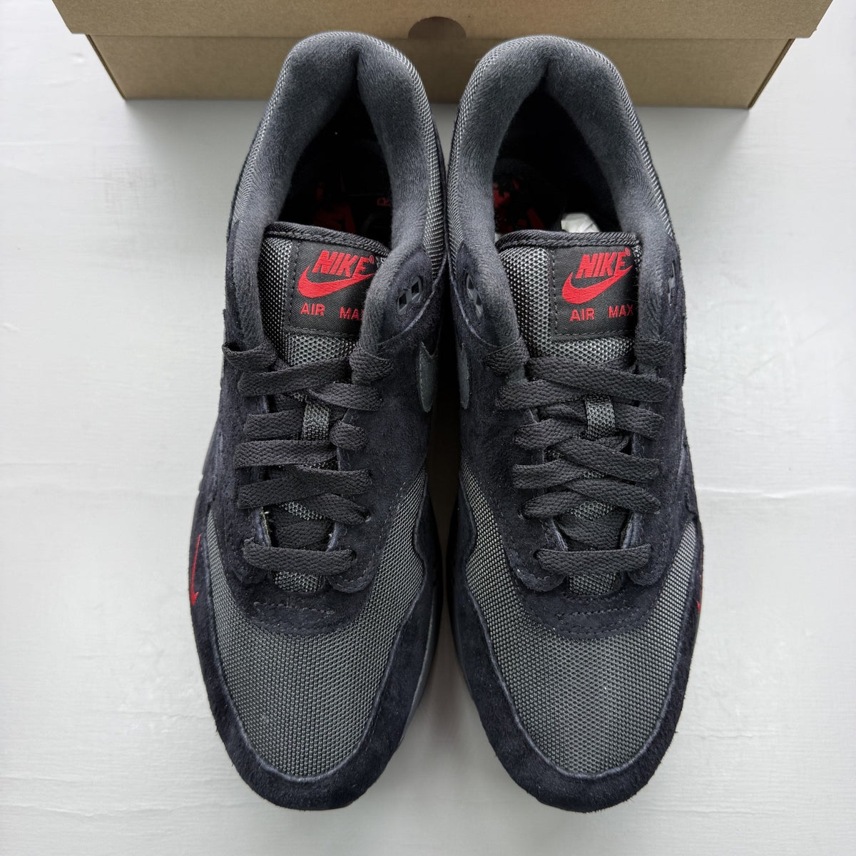 Nike Air Max 1 black trainers with university red accents and logo detail.