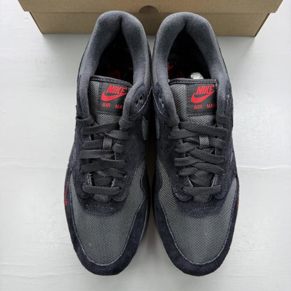 Nike Air Max 1 black trainers with university red accents and logo detail.