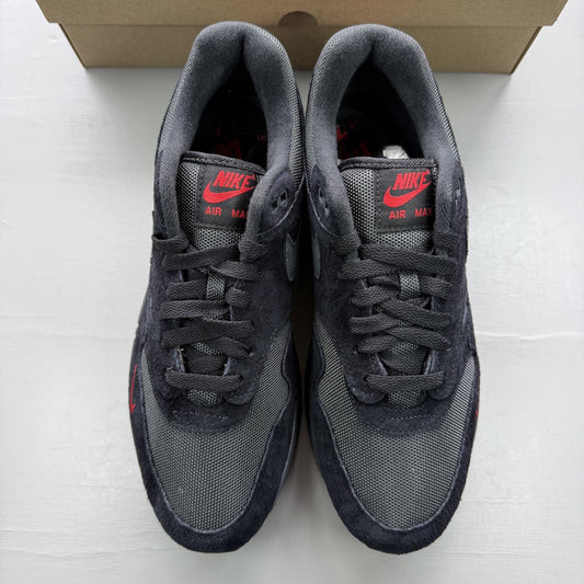 Nike Air Max 1 black trainers with university red accents and logo detail.