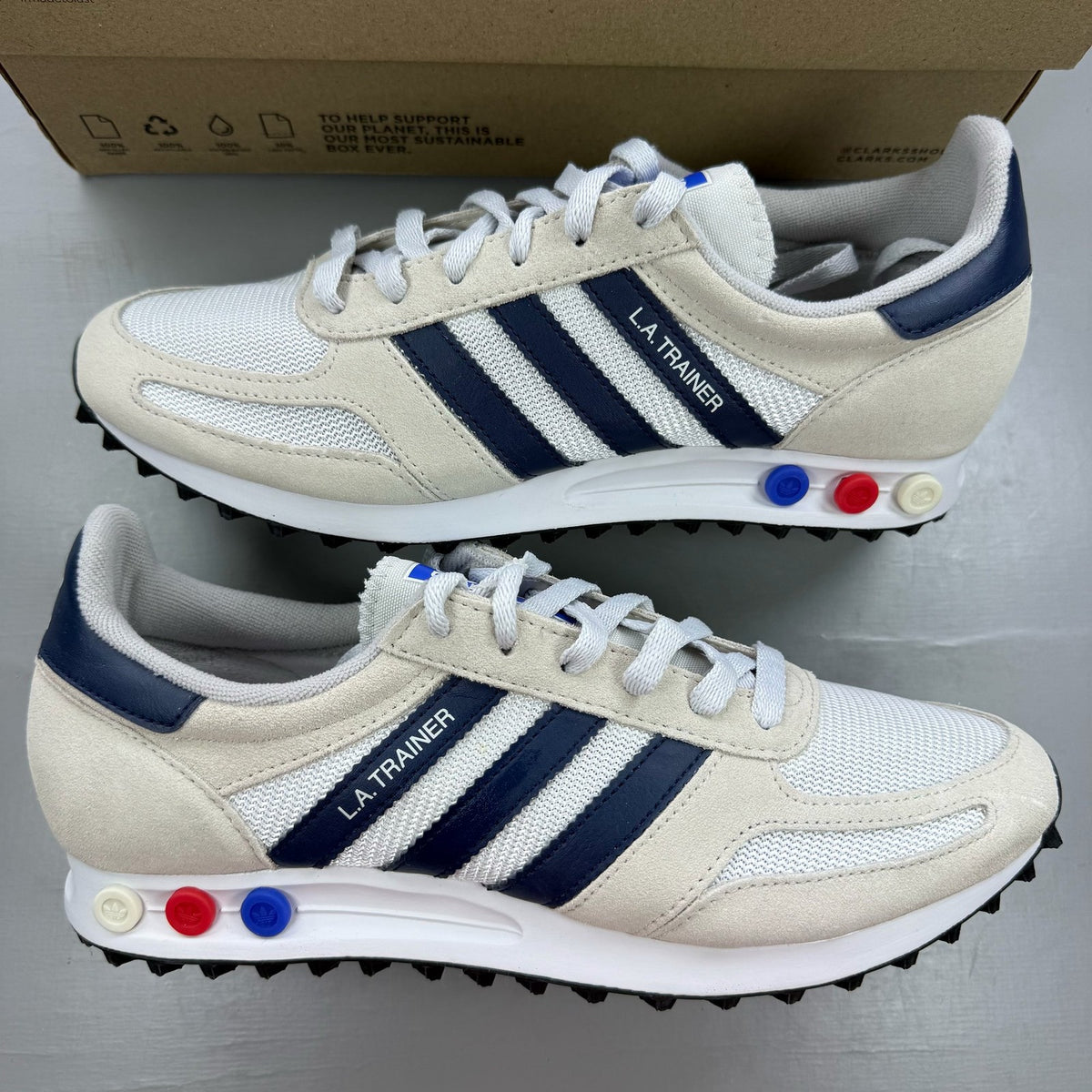 Adidas white LA Trainer sneakers with navy accents and classic three-stripe logo.