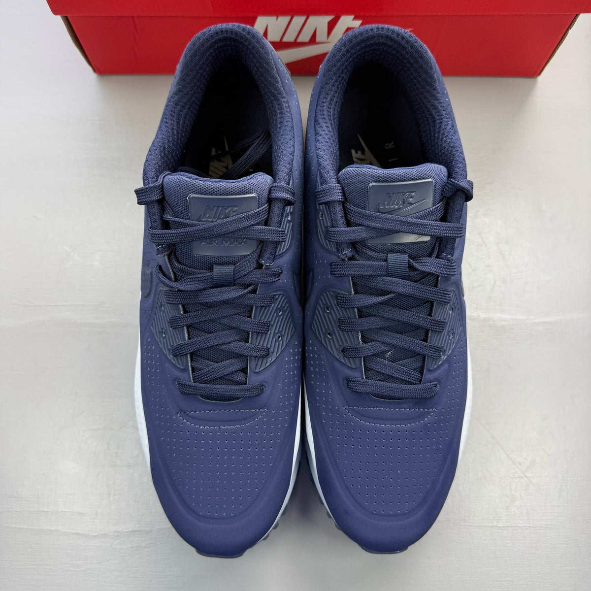 Nike Air Max 90 blue trainers with obsidian accents and logo detail.