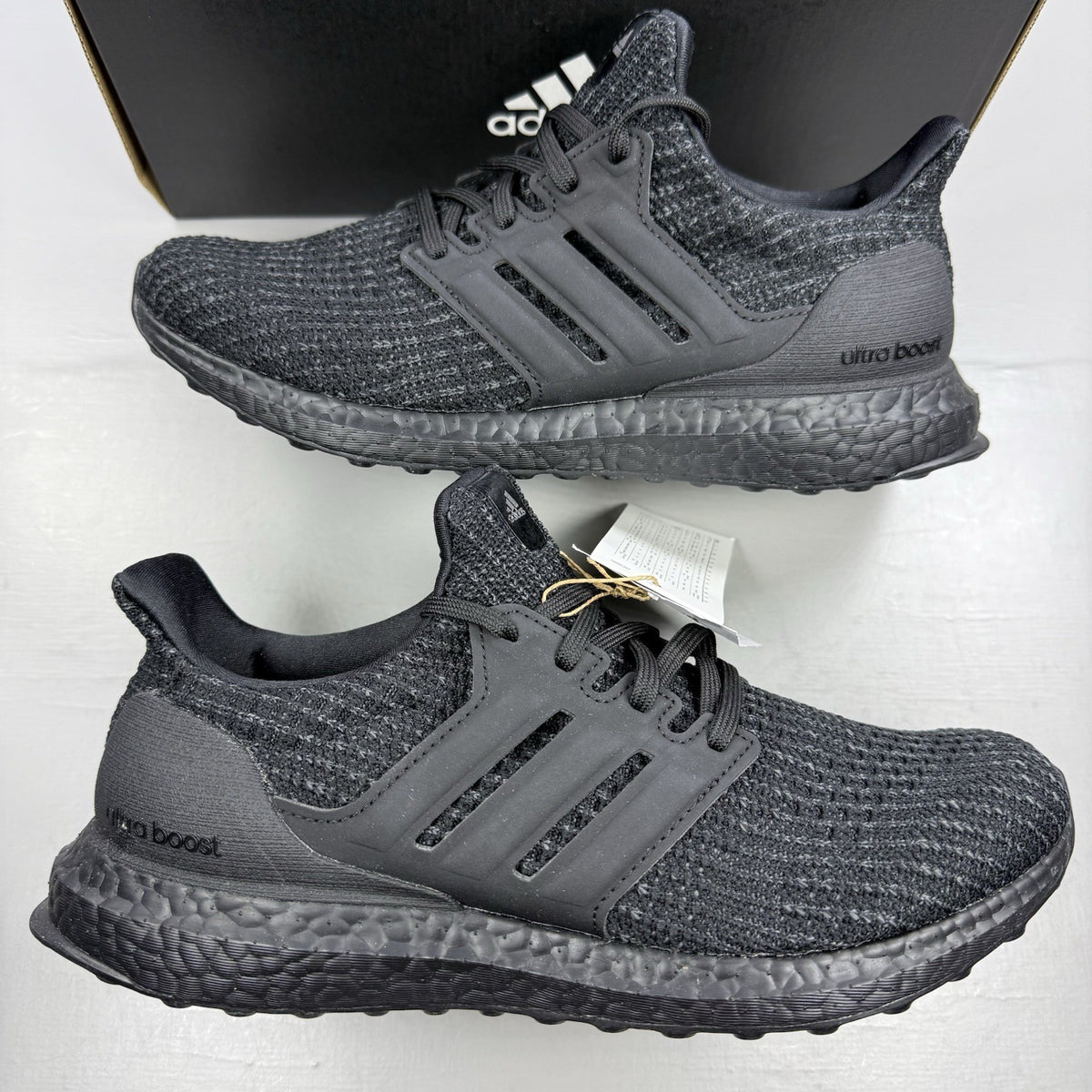 Adidas black trainers with grey accents and signature three-stripe logo.