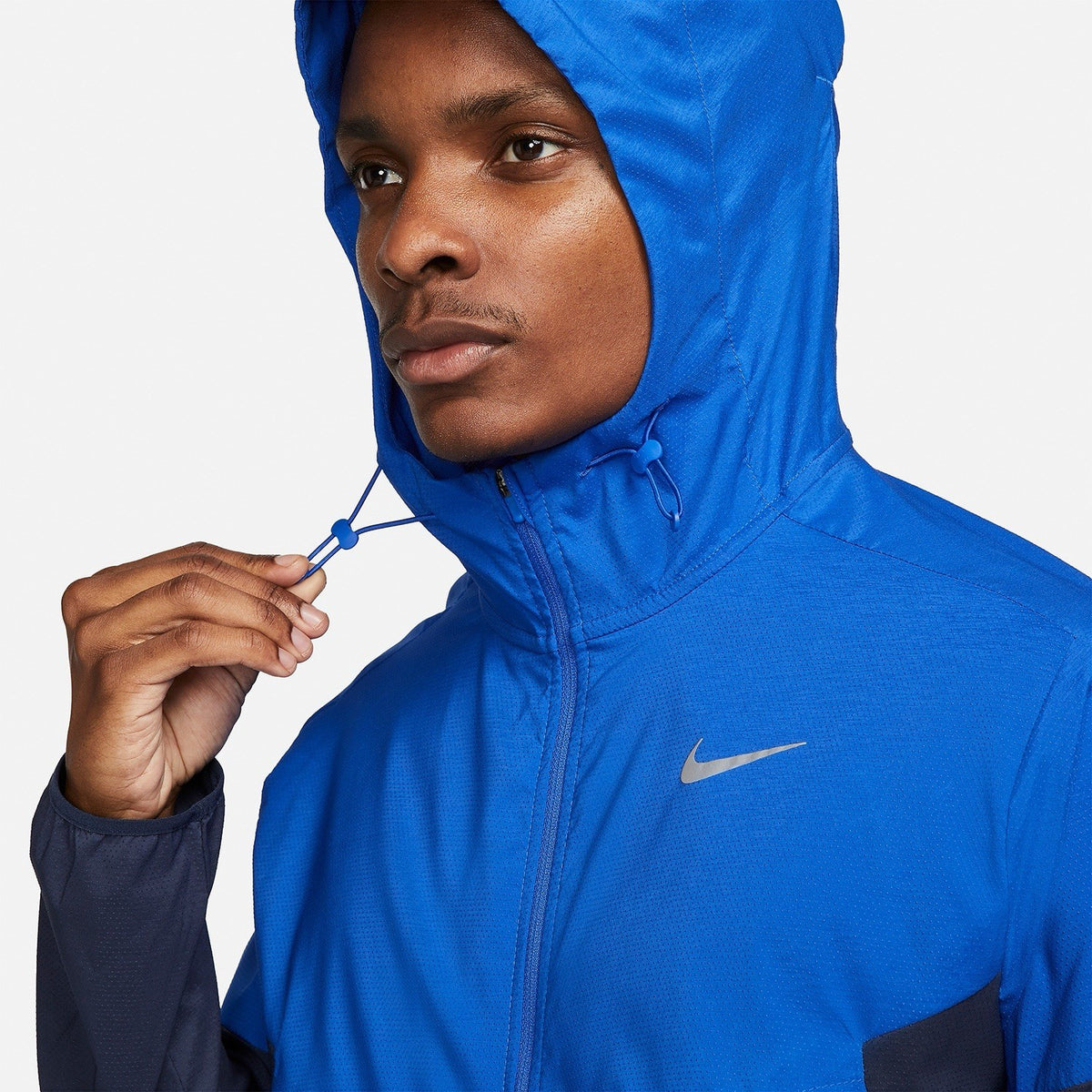 Nike blue Windrunner jacket with logo detail and water-repellent material.