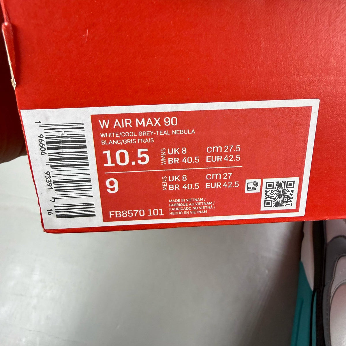 Nike Air Max 90 white trainers with teal accents and visible logo detail.