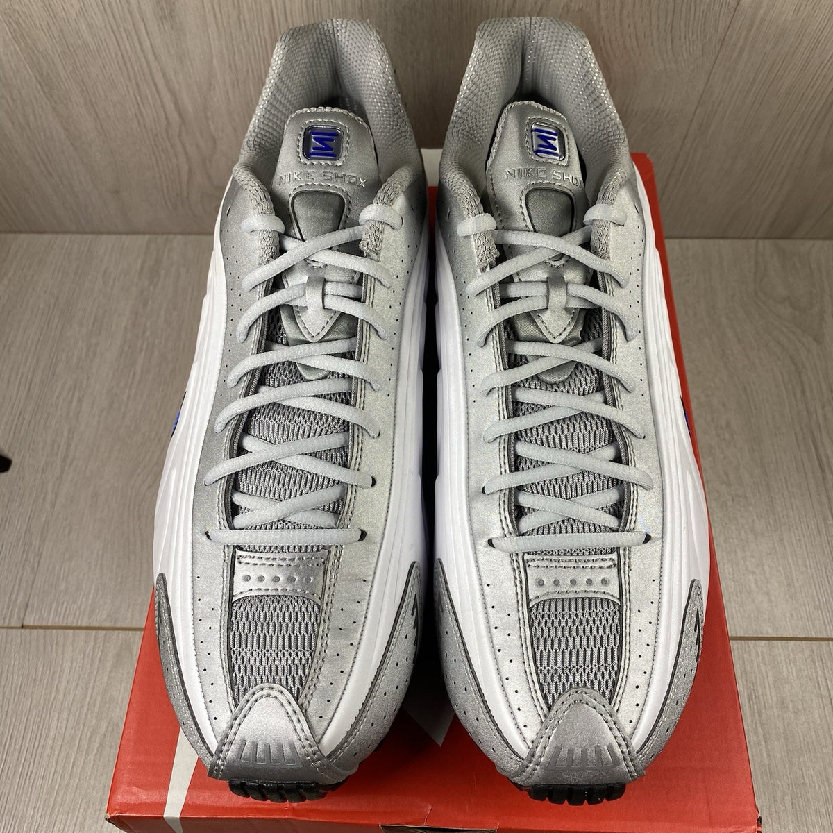 Nike Shox R4 trainers white with blue accents and distinctive Shox cushioning design.