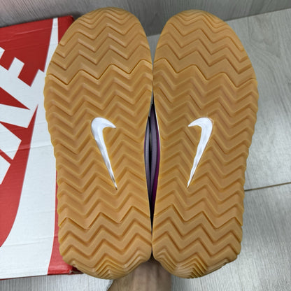 Nike white trainers with pink accents and gum sole, featuring iconic swoosh logo.