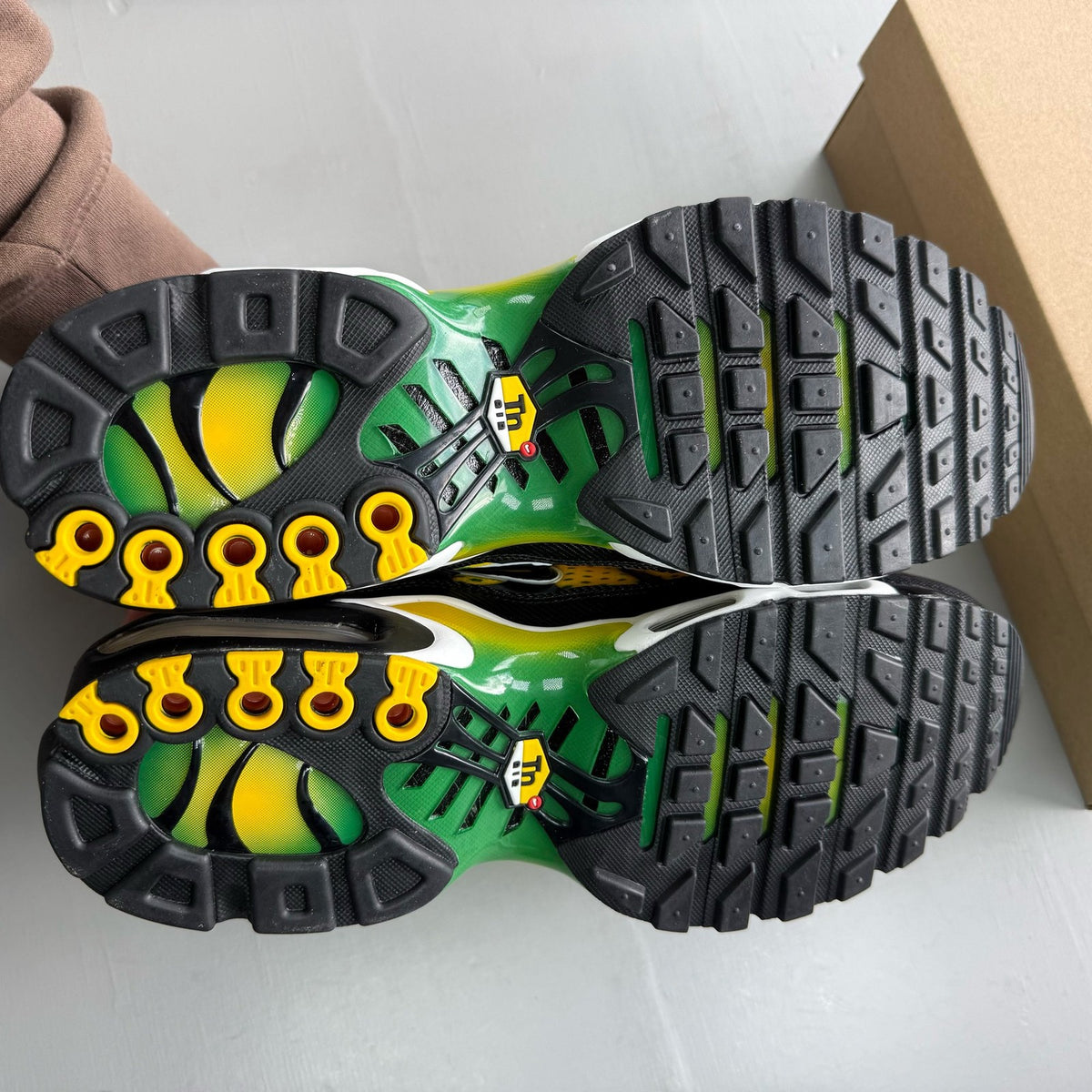 Nike Air Max Plus TN yellow trainers with green accents and signature swoosh logo.
