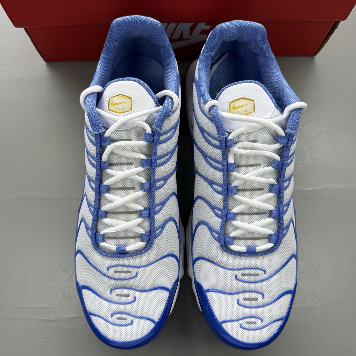 Nike Air Max Plus TN white trainers with blue and yellow accents, mesh upper.