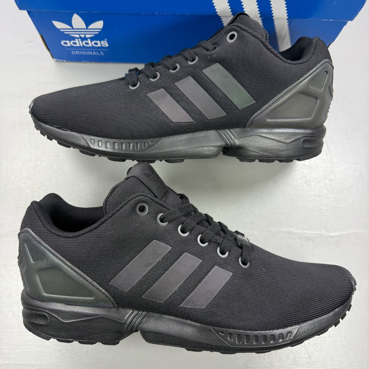 Adidas black trainers with iridescent accents and signature logo on tongue.