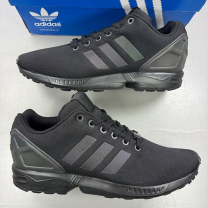 Adidas black trainers with iridescent accents and signature logo on tongue.