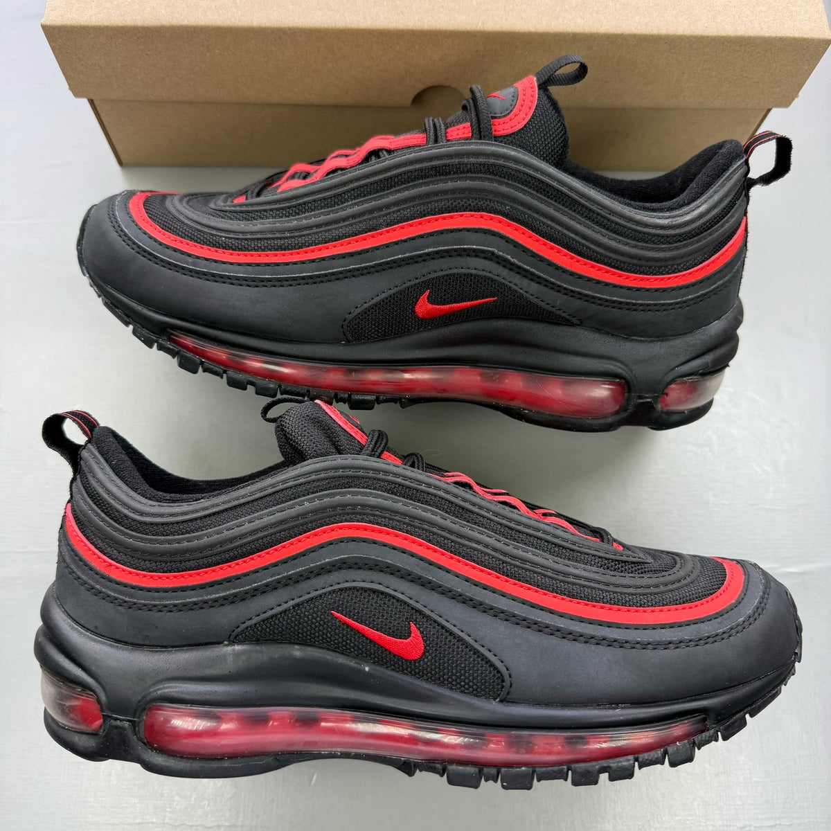 Nike Air Max 97 black trainers with red accents and signature logo details.