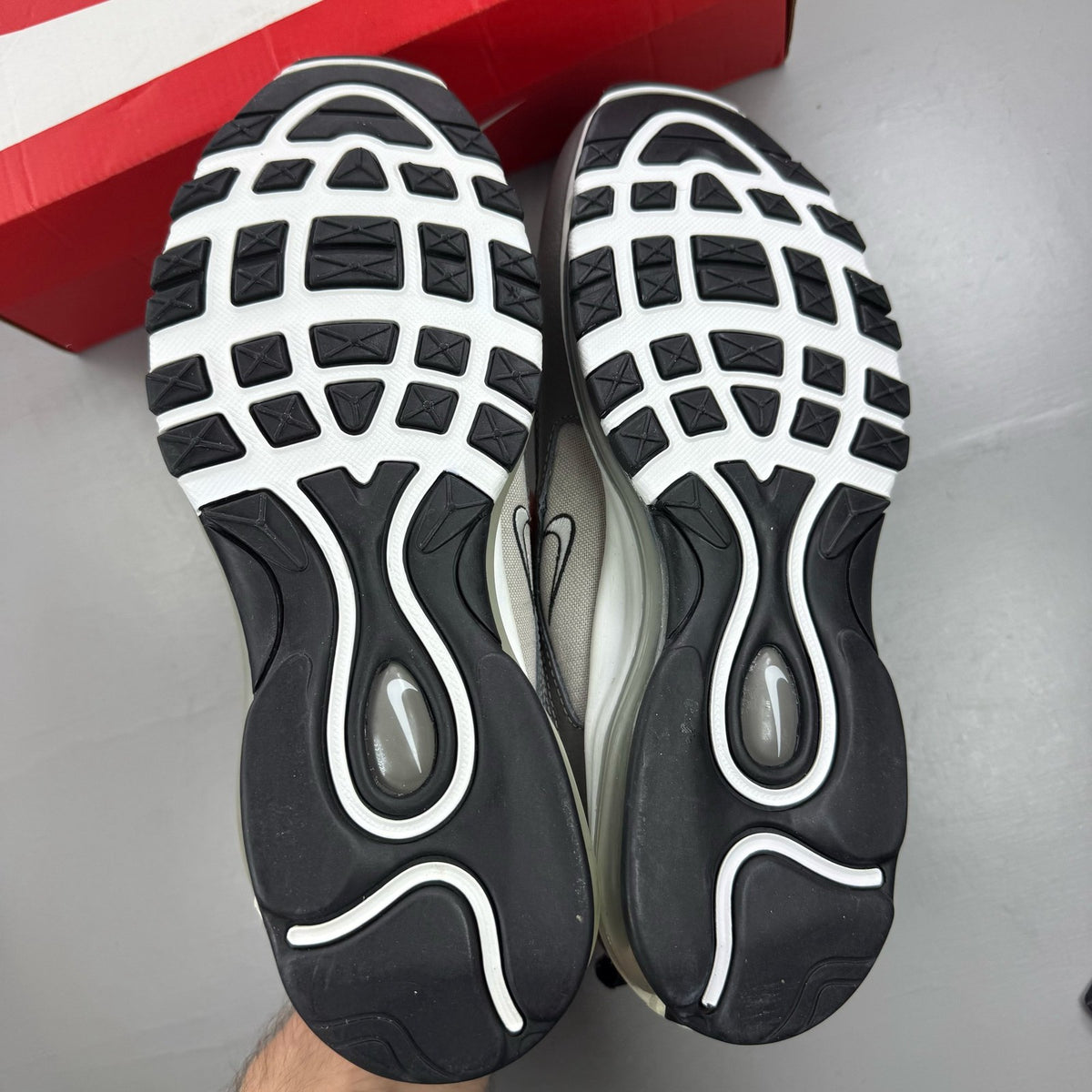 Nike Air Max 97 white trainers with grey and navy accents, featuring iconic swoosh logo.