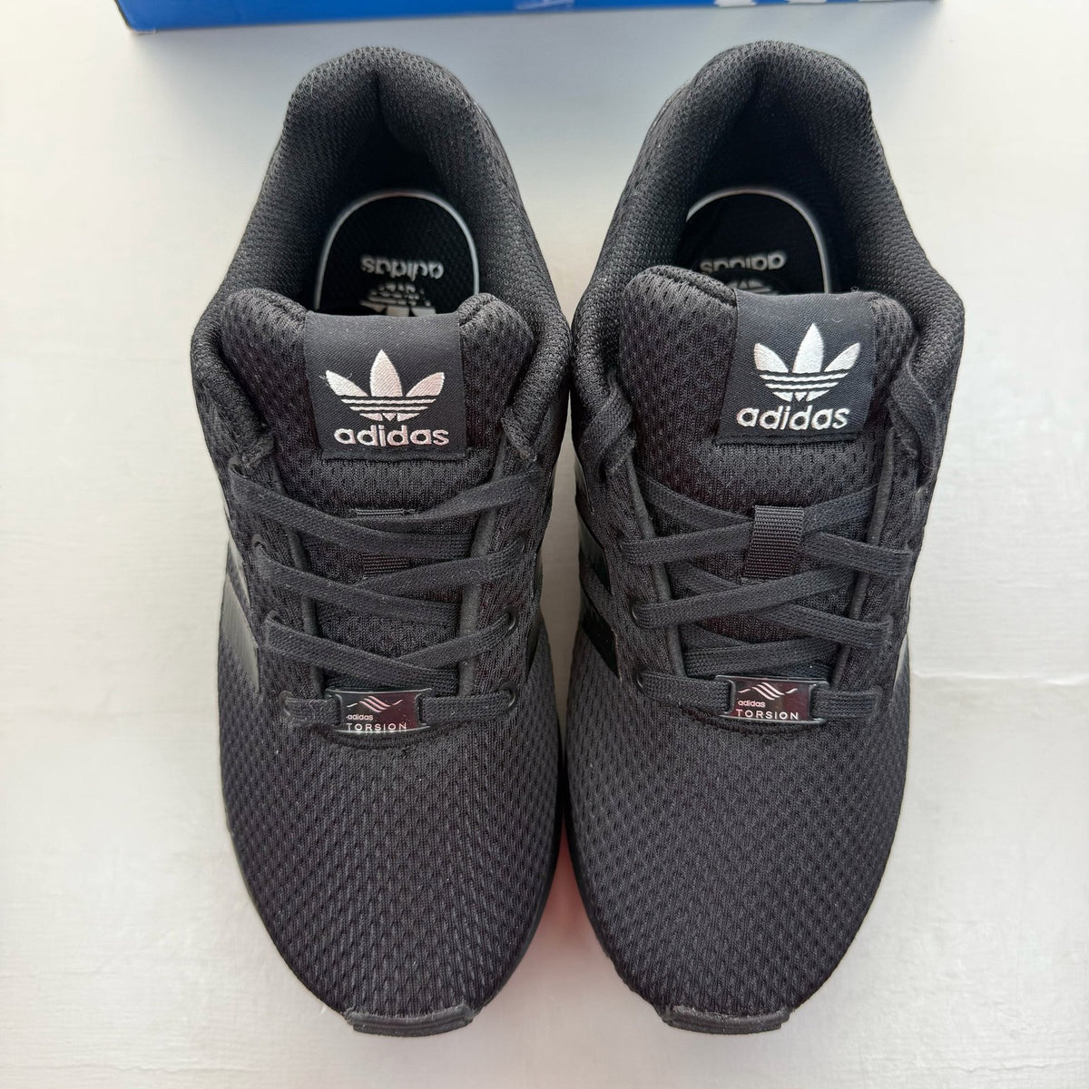 Adidas black trainers with sleek design and logo detail, perfect for kids.