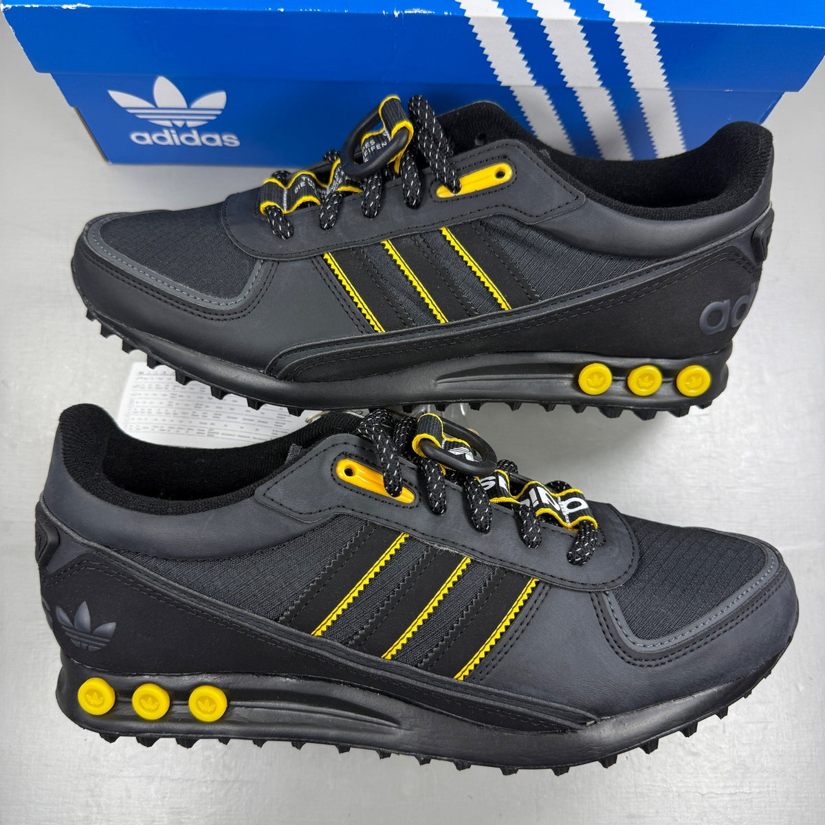 Adidas black deck shoes with gold accents and classic three-stripe logo.