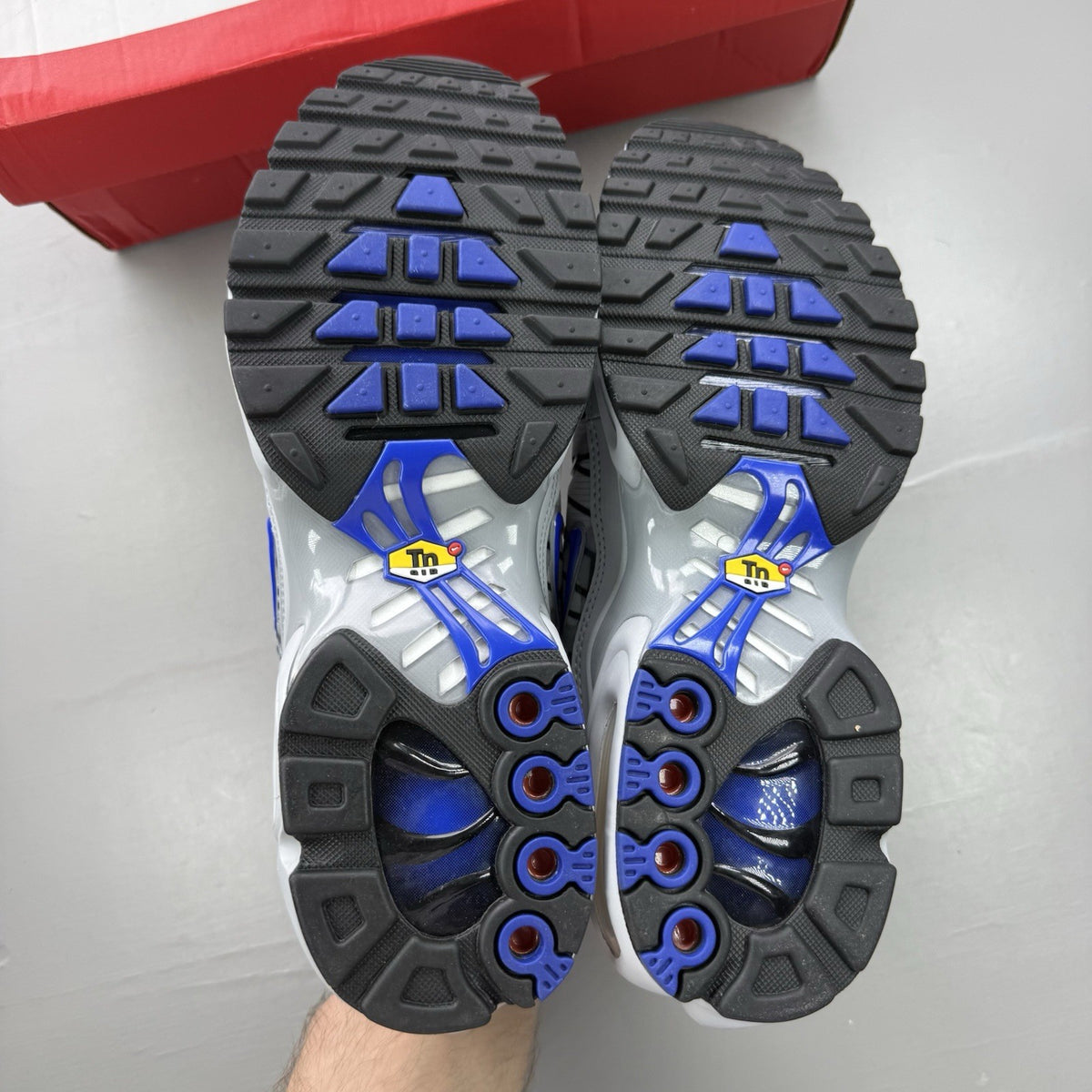 Nike Air Max Plus TN trainers grey with blue accents and signature swoosh logo.