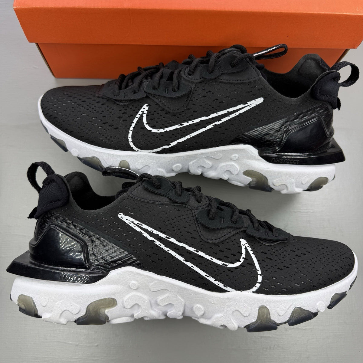 Nike React Vision black trainers with white accents and logo detailing.