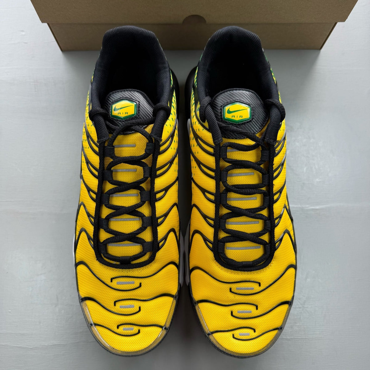 Nike Air Max Plus TN yellow trainers with green accents and signature swoosh logo.