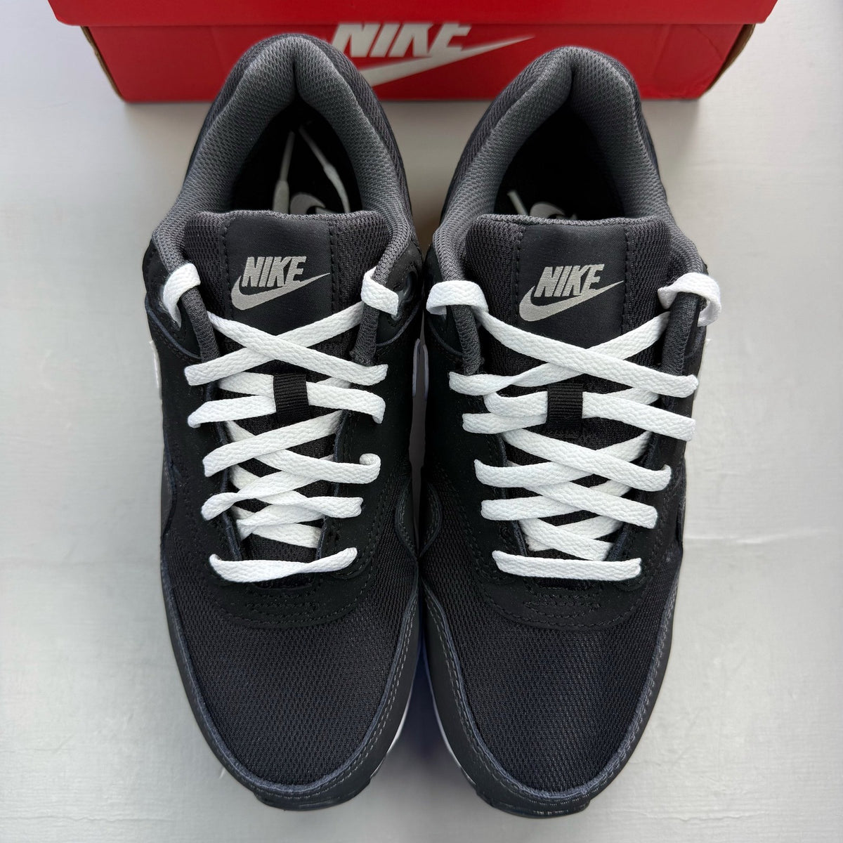 Nike Air Max 1 black trainers with silver and white accents, featuring iconic logo.